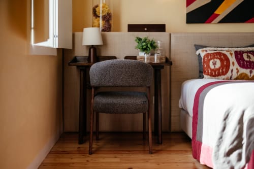 Quarto moderno no Douro Land com cadeira cinzenta, secretária escura, piso de madeira e roupa de cama decorativa com vista para a montanha