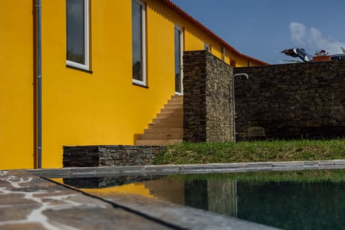 Edifício amarelo vibrante do hotel Douro Land em Peso da Régua com paredes de pedra, escadas de madeira e piscina refletora sob céu azul
