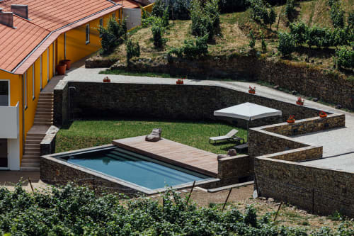 Pátio do hotel Douro Land com piscina retangular, deck de madeira, muros de pedra e vistas sobre os vinhedos em Peso da Régua
