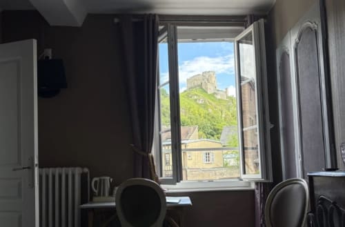 Chambre Villa Aliénor aux Andelys avec bureau, chaises et vue sur les ruines du château depuis la fenêtre