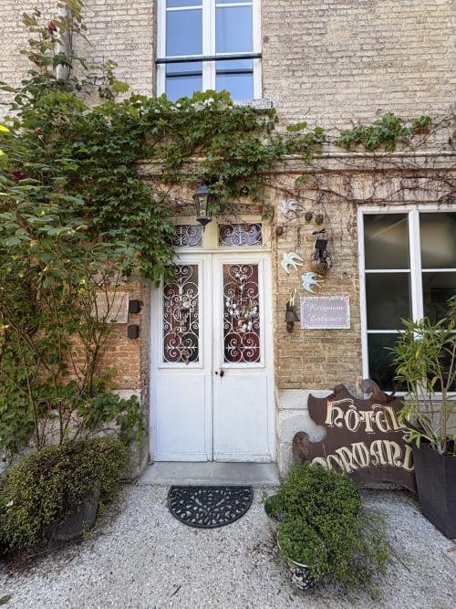 Entrée de la Villa Aliénor aux Andelys avec portes blanches, murs couverts de lierre et plantes en pots