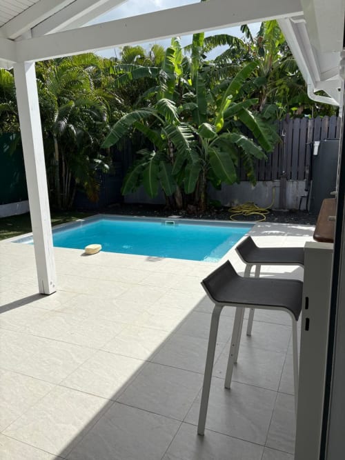 Villa avec piscine privée à Maly Blue Location, Le Moule, dotée de chaises longues et de plantes tropicales sous une pergola blanche