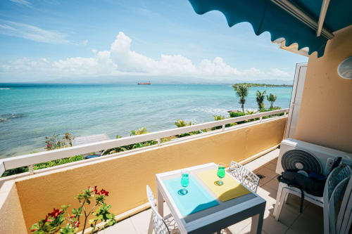 Balcony with sea view at La Perle Fleur D'Epée, Le Gosier, featuring turquoise Caribbean waters and white clouds