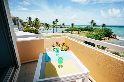 Beachfront balcony at La Perle Fleur d'Epée hotel in Le Gosier with sea view, tropical palms, and turquoise waters