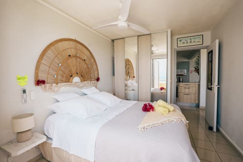 Bright bedroom at La Perle Fleur D'Epée, Le Gosier with woven headboard, mirrored wardrobe, and sea view balcony access