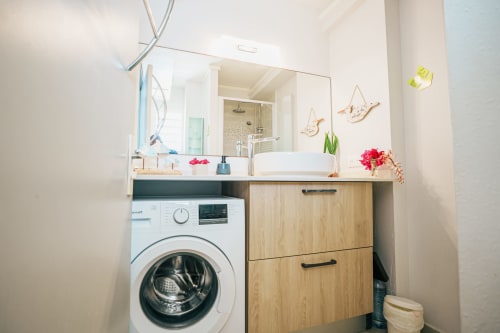 Modern bathroom vanity with washer in La Perle Fleur D'épée apartment, Le Gosier