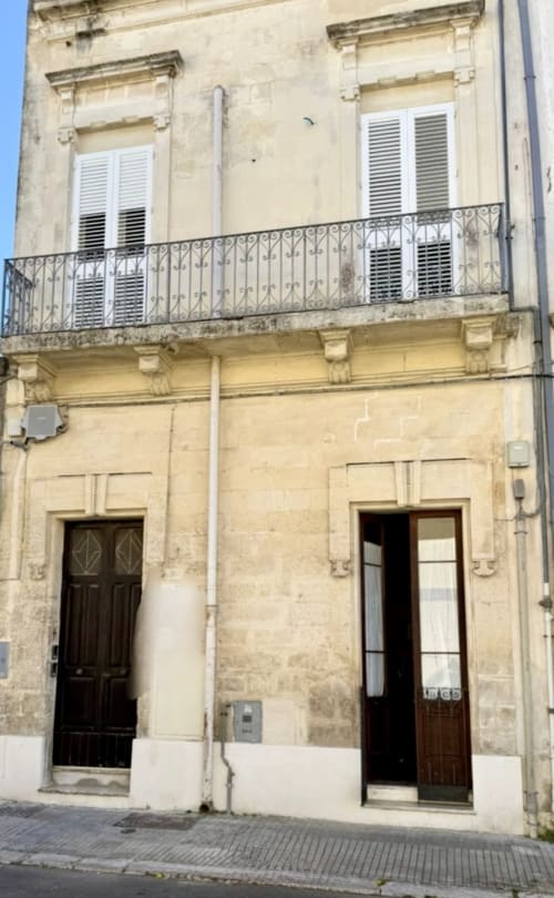 Storica facciata in pietra leccese a Lecce con balconate in ferro battuto, porte in legno e finestre con persiane - HABITARE Lecce &