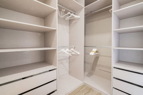 Espaçoso guarda-roupa com prateleiras brancas, gavetas e cabideiros no apartamento BlueHorizon em SignatureStays Albufeira