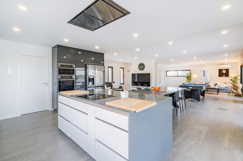 Cozinha aberta e área de estar moderna no apartamento BlueHorizon, Albufeira, com bancada central e acabamentos em aço inoxidável