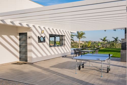 Terraço moderno com mesa de ping-pong, espreguiçadeiras, vista para a piscina e jardim exuberante em Albufeira
