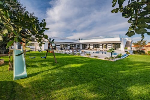 Apartamento BlueHorizon em Albufeira com edifício moderno branco, relvado verde, parque infantil, piscina e espreguiçadeiras