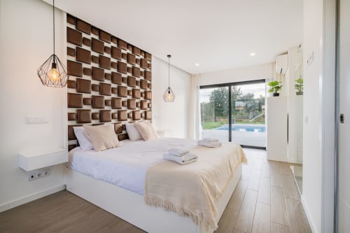 Quarto moderno no BlueHorizon by SignatureStays em Albufeira com cabeceira geométrica, luminárias pendentes e vista para a piscina