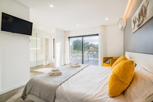 Quarto moderno em BlueHorizon em Albufeira com vista para a piscina, detalhes amarelos, banheiro integrado e acesso ao terraço