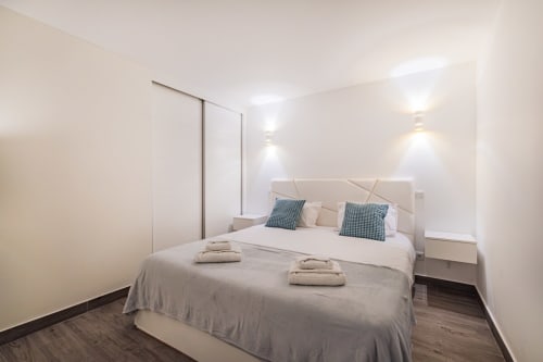 Quarto moderno na BlueHorizon by SignatureStays em Albufeira com cama queen, almofadas azuis e iluminação contemporânea