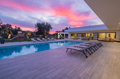 Apartamento BlueHorizon em Albufeira com vista do pôr do sol, piscina iluminada, espreguiçadeiras e edifício moderno ao entardecer