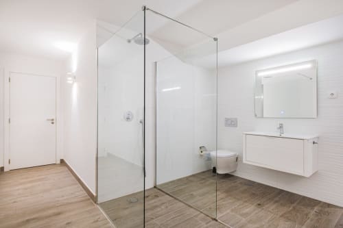 Casa de banho moderna no BlueHorizon by SignatureStays em Albufeira com chuveiro de vidro, lavatório branco e piso em madeira