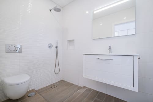 Banheiro moderno e branco no apartamento BlueHorizon da SignatureStays Albufeira com pia suspensa e chuveiro tipo walk-in