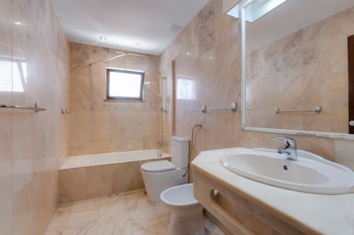 Casa de banho moderna no apartamento Beachtime Oura, Albufeira, com azulejos de mármore, lavatório elegante, sanitário e boxe de duche