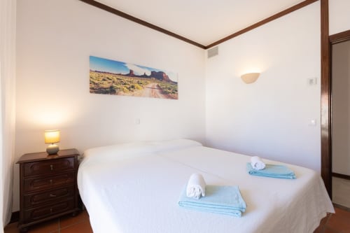 Quarto luminoso na Beachtime Oura by SignatureStays em Albufeira com cama branca, arte de paisagem desértica e madeira