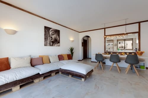Apartamento de plano aberto moderno em Beachtime Oura, Albufeira, com assentos de paletes, balcão de cozinha e decoração contemporânea.