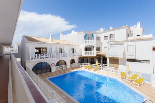Apartamento Beachtime Oura em Albufeira com piscina, arquitetura mediterrânea branca e espreguiçadeiras amarelas