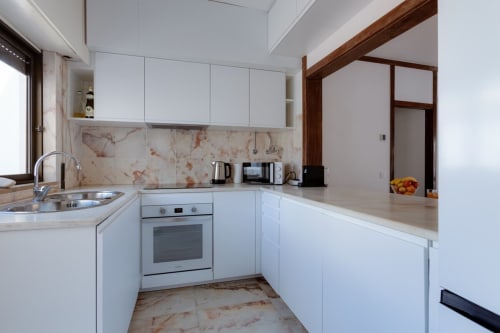 Cozinha moderna branca com backsplash e bancadas em mármore do apartamento Beachtime Oura em Albufeira