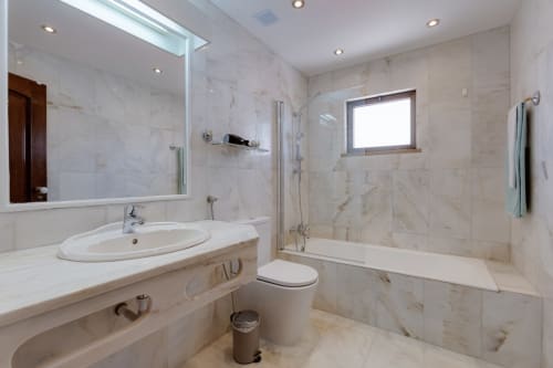 Casa de banho moderna com lavatório oval, box com vidro e janela no apartamento Beachtime Oura em Albufeira