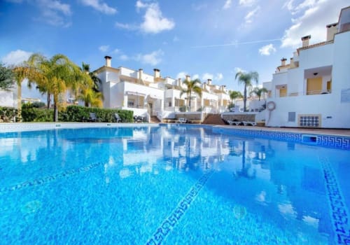 Piscina de águas cristalinas no Farmvillage by SignatureStays em Albufeira, com edifícios brancos e palmeiras