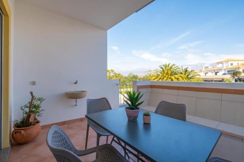 Varanda moderna em Albufeira com mesa azul, plantas em vasos e vista para o mar na Farmvillage by SignatureStays