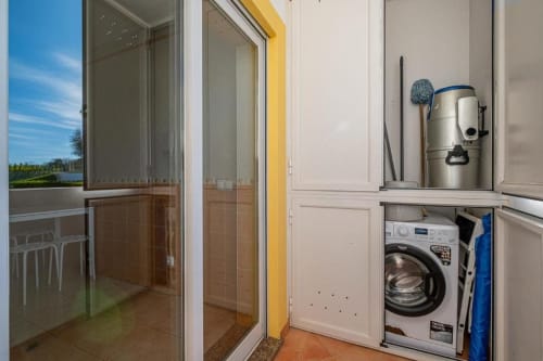 Lavandaria com máquina de lavar e produtos de limpeza no apartamento Farmvillage em Albufeira