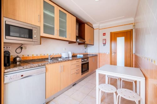 Cozinha moderna com armários em madeira, bancada em granito e mesa de jantar no apartamento Farmvillage em Albufeira, Algarve