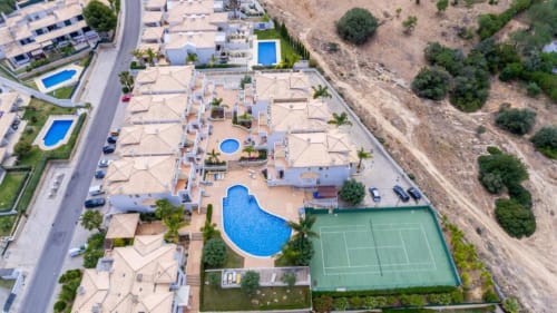 Vista aérea do Farmvillage apartments em Albufeira com piscina, quadra de ténis e paisagem mediterrânea