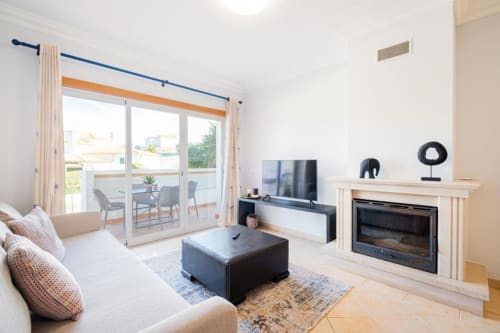 Apartamento luminoso em Albufeira com lareira, TV, sofá bege e varanda com vista para o terraço na SignatureStays