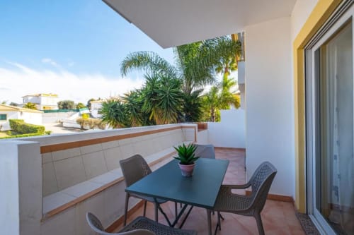 Terraço da varanda do apartamento Farmvillage em Albufeira com mesa de jantar, cadeiras e vistas para palmeiras