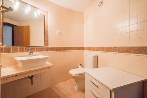 Casa de banho moderna do apartamento Capetown Marina em Albufeira com azulejos, lavatório, sanita e armário de arrumação.