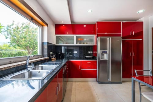 Cozinha moderna vermelha com eletrodomésticos em aço inoxidável no apartamento Capetown Marina, Albufeira