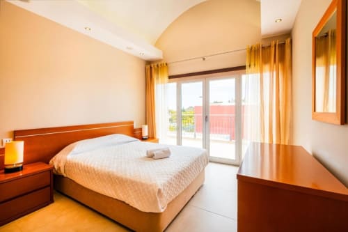 Quarto espaçoso em Capetown Marina by SignatureStays em Albufeira com móveis em madeira, roupa de cama branca e acesso à varanda