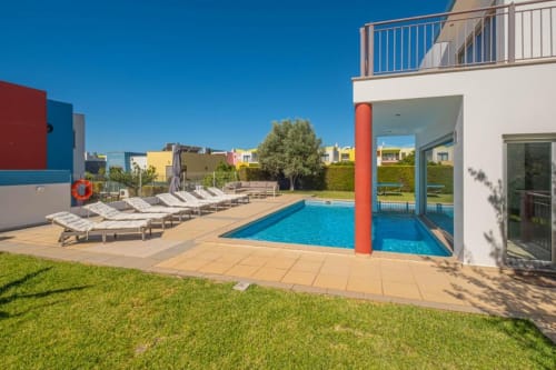 Piscina do apartamento Capetown Marina em Albufeira com espreguiçadeiras, edifício branco moderno e arquitetura colorida