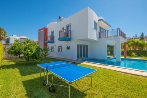 Villa moderna branca em Albufeira com piscina azul, mesa de pingue-pongue e jardim impecável