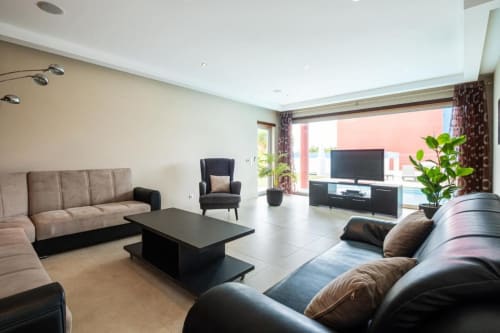 Sala de estar moderna e espaçosa no Capetown Marina SignatureStays Albufeira com áreas de estar, TV e vista para o terraço