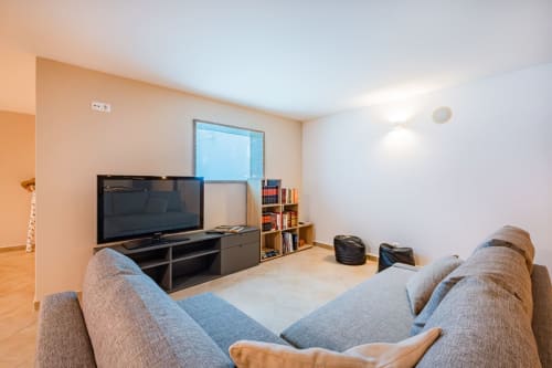 Sala de estar moderna no Capetown Marina em Albufeira com sofá cinzento, TV de ecrã plano e estantes de arrumação.