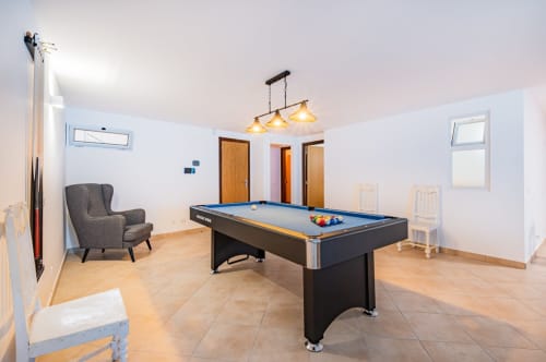 Espaçosa sala de jogos do apartamento Capetown Marina em Albufeira com mesa de bilhar, poltrona e iluminação pendente