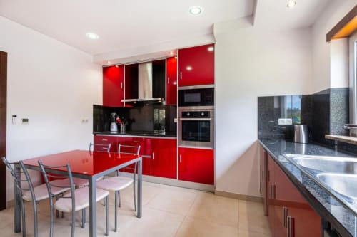 Cozinha moderna vermelha com área de refeições em apartamento Marina de Capetown, Albufeira