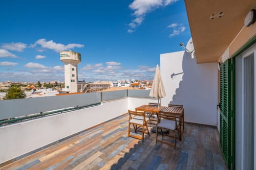 Terraço na cobertura com deck de madeira, mesa de jantar e vista para a cidade de Albufeira no apartamento Heart of Oura