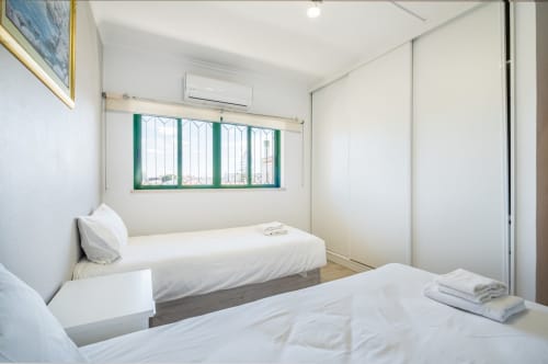 Quarto geminado luminoso no Heart of Oura by SignatureStays em Albufeira com janela de moldura verde e ar-condicionado