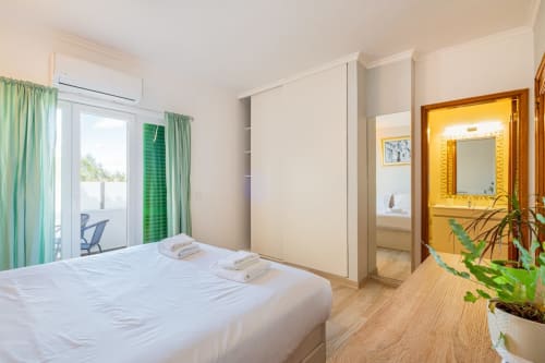 Quarto moderno no Heart of Oura, Albufeira com cama queen, cortinas verdes, casa de banho privativa e acesso à varanda