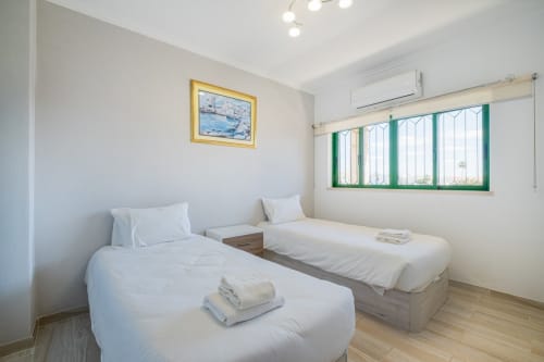 Quarto duplo no apartamento Heart of Oura no SignatureStays Albufeira com roupa de cama branca e persianas verdes