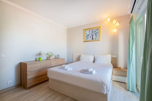 Quarto moderno no apartamento Heart of Oura, Albufeira, com cama de casal, cômoda de madeira e cortinas verdes