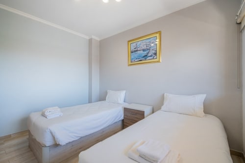 Quarto duplo do apartamento Heart of Oura em Albufeira com camas de madeira, roupa de cama branca e decoração náutica em paredes claras.