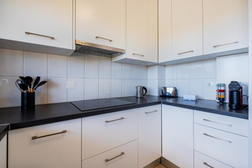 Cozinha moderna branca com bancada preta no apartamento Heart of Oura em Albufeira